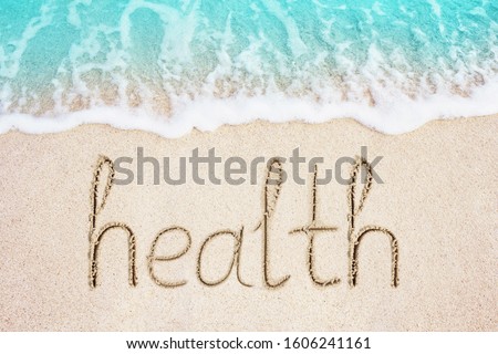 Health word written in the sand, beach and blue wave on background. Concept photo.