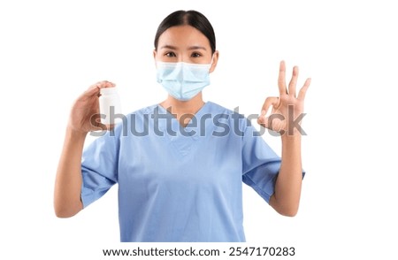 Health worker in blue scrubs holds a medicine bottle and shows an okay gesture, isolated on white background.