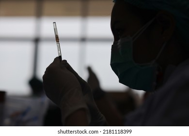 Health Worker A Nurse Is Preparing A Syringe To Inject A Sick Person In The Hospital. Silhouette. Selective Focus.