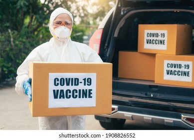 the health worker wearing the protective suit during loading COVID-19's vaccine to the car's cargo. the concept of transportation, vaccine, coronavirus pandemic and medical