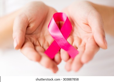 healthcare, charity, people and medicine concept - close up of woman cupped hands holding pink cancer awareness ribbon - Shutterstock ID 303887858