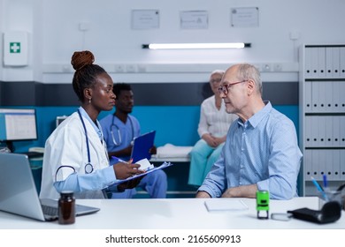 Healthcare clinic specialist taking notes about sick elderly patient health condition while recommending advanced consultation and examination. Hospital practitioner writing on clipboard illness - Shutterstock ID 2165609913