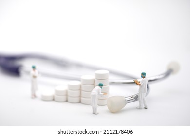 Healthcare Concept. Closeup Of Group Of Doctor Miniature Figure With Patient File Standing With Stack Of Pills And Stethoscope On White Background.