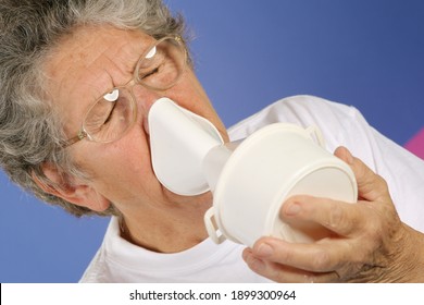 concept de soins de santé, rhumes, rhinites et maux de gorge. La vieille femme aux cheveux gris utilise un inhalateur pour insuffler la médecine et se guérir.