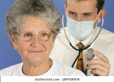 Healthcare concept. Doctor with stethoscope examines sick old woman in consultation. The patient in the foreground is over 65 years old with glasses and gray hair.