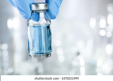 Healthcare concept with a hand in blue medical gloves holding a vaccine vial with blue liquid