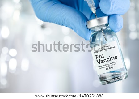 Healthcare concept with a hand in blue medical gloves holding Flu, Influenza, vaccine vial