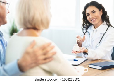 Healthcare Concept. Hispanic Doctor Showing Pills To Her Mature Patients, Senior Couple Listening, Empty Space