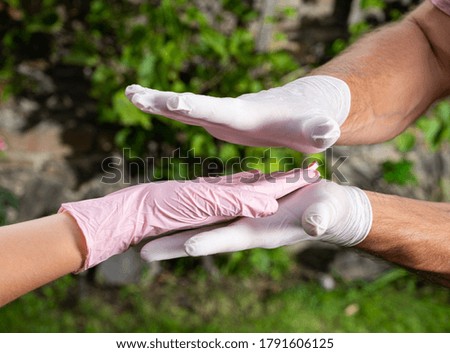 Healthcare concept. Man  in protective gloves holding woman's hand in glove  outdoors