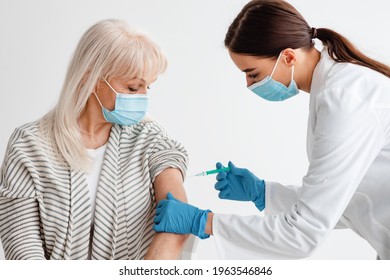 Healthcare Concept. Medical Doctor Or Nurse In Surgical Mask Giving Coronavirus Vaccine Shot To Senior Woman At Hospital. Older Female Patient Getting Covid-19 Vaccine. Immunization Campaign