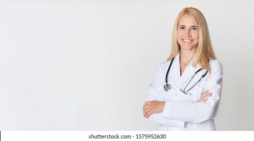 Healthcare concept. Middle-aged woman doctor in uniform and with stethoscope, posing over grey background. Panorama with free space