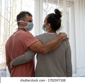 Healthcare concept. Sad couple in masks posing near window at home - Shutterstock ID 1702597108