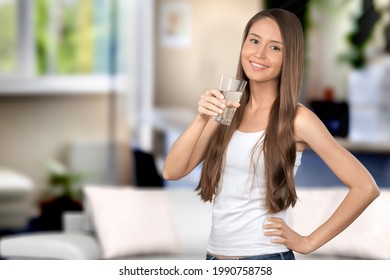 Healthcare concept. A woman sits in a living room, holding a glass of water in a hand - Shutterstock ID 1990758758