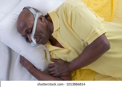 Healthcare concept,African, American Man with obstructive sleep apnea sleeping well with cpap machine ,Man laying in bed wearing  mask, on white