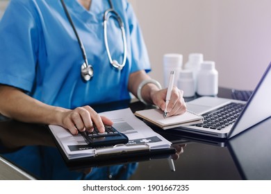 Healthcare costs and fees concept.Hand of smart doctor used a calculator and smartphone, tablet for medical costs at hospital 
