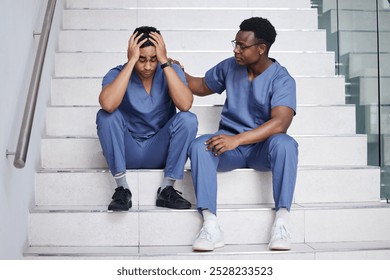 Healthcare, doctors and support in hospital for mistake, surgical error and comfort for mental health. Surgeon, friend and upset on stairs with trust, consoling or frustrated in profession for crisis - Powered by Shutterstock