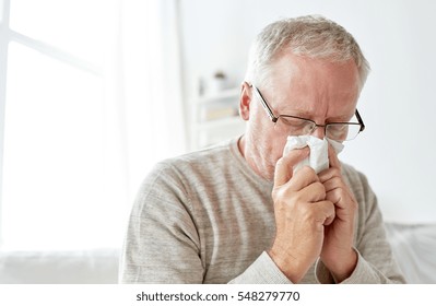 healthcare, flu, hygiene and people concept - sick senior man with paper wipe blowing his nose at home - Powered by Shutterstock