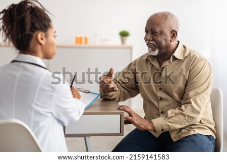 Healthcare, Geriatric Medicine, Medical Check Up. Senior man visiting doctor telling about health complaints, female gp or nurse writing personal information, filling form listening to elderly patient Stock fotó © 