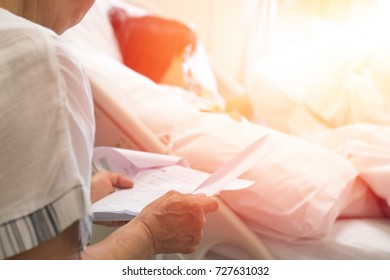 Healthcare Health Insurance Concept. Parent Looking At Invoice Or Receipt Paper Document From Hospital Payment Department Expenses Of Ill Kid Patient 