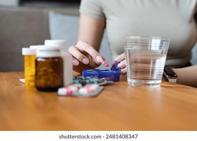 Healthcare at Home: Woman Organizing Pills with Medication Bottles and Water Glass on Wooden Table for Daily Health Management - Powered by Shutterstock