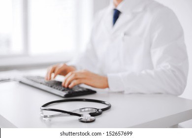 healthcare, hospital and medicine concept - male doctor typing on the keyboard