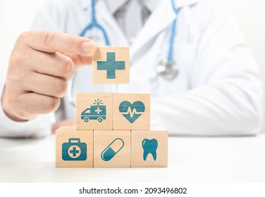 Healthcare and Insurance concept. Doctor hand choose cross sign on wood cube block. Health care insurance or service concept. Medical healthcare icons on stacked wooden cubes