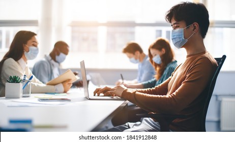 Healthcare, Lifestyle And People Concept. Group of diverse international students or employees wearing protective medical masks and using laptop computers, studying and working. New Normal