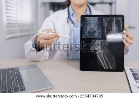 Healthcare and medical concept, Asian female doctor using digital tablet with Patient x-ray film at doctor's office in hospital.