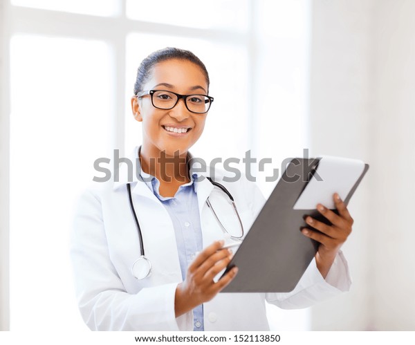 healthcare and medical concept -\
smiling african female doctor with prescription in\
hospital