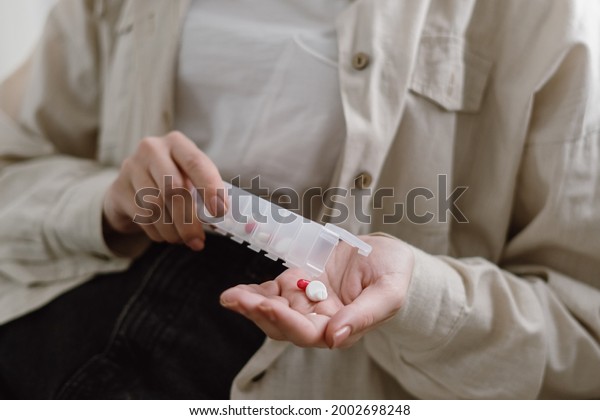 Healthcare and medicamentation treatment concept.\
Cropped view of young sick woman grab round pills from organizer\
box, taking prescription supplements and vitamins, painkiller for\
ache relief