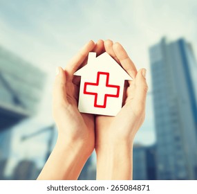 Gesundheitswesen, Medizin und Wohltätigkeitskonzept - Hände, die weißes Papierhaus mit rotem Kreuz halten
