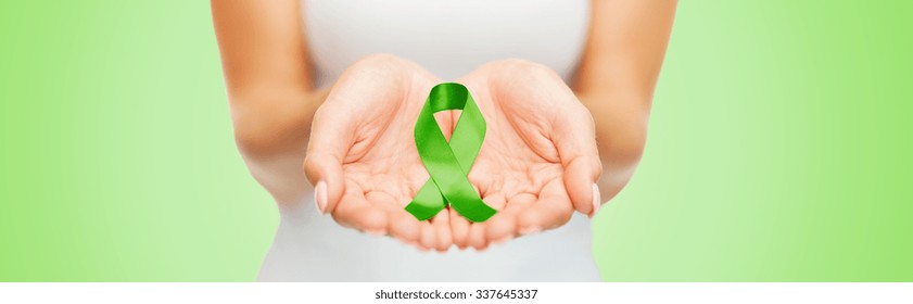 Healthcare And Medicine Concept - Close Up Of Woman Hands Holding Green Organ Transplant Awareness Ribbon