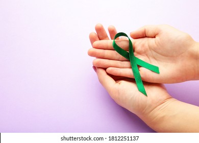 Healthcare And Medicine Concept - Female Hands Holding Green Organ Transplant Awareness Ribbon. Top View