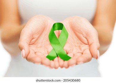 Healthcare And Medicine Concept - Female Hands Holding Green Organ Transplant Awareness Ribbon