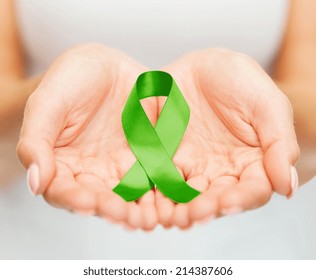 Healthcare And Medicine Concept - Female Hands Holding Green Organ Transplant Awareness Ribbon