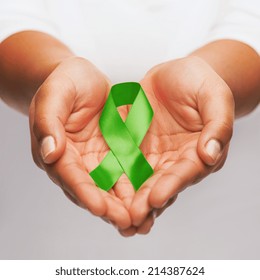 Healthcare And Medicine Concept - Female Hands Holding Green Organ Transplant Awareness Ribbon