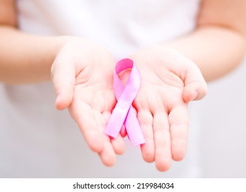 healthcare and medicine concept - girl hands holding pink breast cancer awareness ribbon - Shutterstock ID 219984034