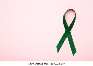 Healthcare And Medicine Concept. Green Organ Transplant Awareness Ribbon On Pink Background.