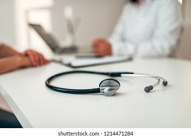 Healthcare and medicine concept. Medical stethoscope on desk. Doctor and patient in the background. Focus on the foreground, on the stethoscope.