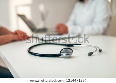 Healthcare and medicine concept. Medical stethoscope on desk. Doctor and patient in the background. Focus on the foreground, on the stethoscope.