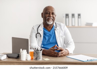 Healthcare And Medicine Concept. Portrait of cheerful mature African American doctor posing, smiling looking at camera, sitting at desk in office. Trustworthy specialist in stethoscope and white coat - Powered by Shutterstock