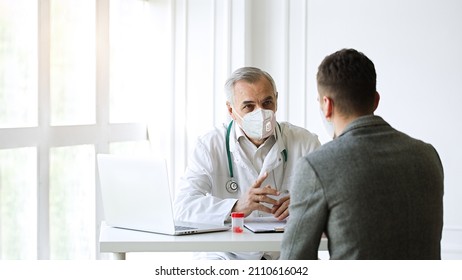 Healthcare, Medicine Concept: Senior Doctor In Wearing FFP2 Face Mask During Coronavirus Covid-19 Infection Pandemic Consults Young Patient