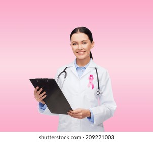 healthcare and medicine concept - smiling female doctor with stethoscope, clipboard and pink cancer awareness ribbon over pink background