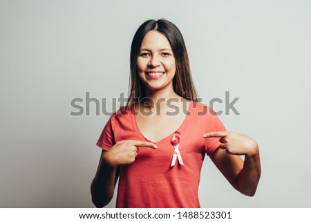 Healthcare and medicine concept - woman in t-shirt with pink breast cancer awareness ribbon
