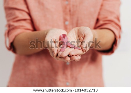 Healthcare and medicine concept - womans hands holding pink breast cancer awareness ribbon