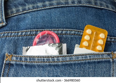 Healthcare medicine, contraception and birth control. Closeup oral contraceptive pills, condom in denim pocket.