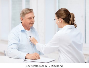 Healthcare, Medicine And Elderly Concept - Female Doctor Or Nurse With Old Man Listening To Heart Beat