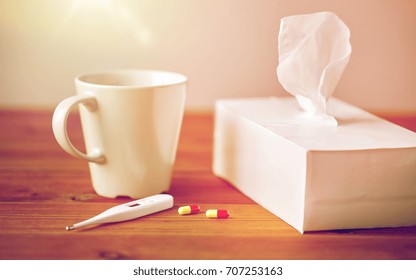 Healthcare, Medicine, Flu And Treatment Concept - Cup Of Tea, Paper Wipes And Thermometer With Pills