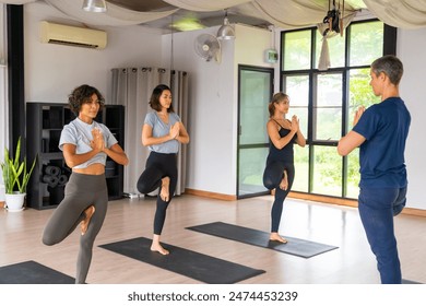 Healthcare motivation, sport training yoga class at fitness gym. Group of Asian woman enjoy healthy lifestyle practicing yoga exercise and body stretching with instructor on yoga mat in studio room. - Powered by Shutterstock