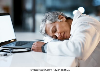 Healthcare, overtime and doctor sleeping at laptop, burnout and exhausted from research with mockup. Stress, sleep and woman in medicine at desk, tired and napping at work late at night in hospital. - Shutterstock ID 2254585501